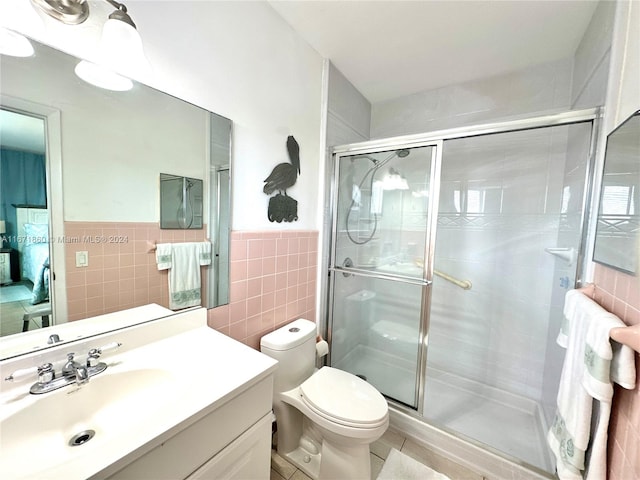 bathroom featuring a shower with shower door, toilet, tile patterned floors, tile walls, and vanity