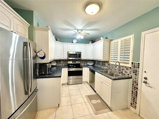 kitchen featuring tasteful backsplash, appliances with stainless steel finishes, sink, white cabinets, and light tile patterned floors