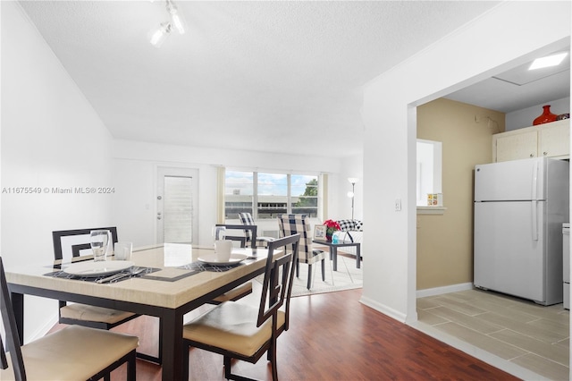 dining space with a textured ceiling and light hardwood / wood-style flooring