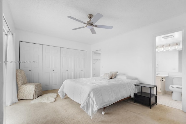 bedroom featuring a closet, light carpet, ceiling fan, and connected bathroom