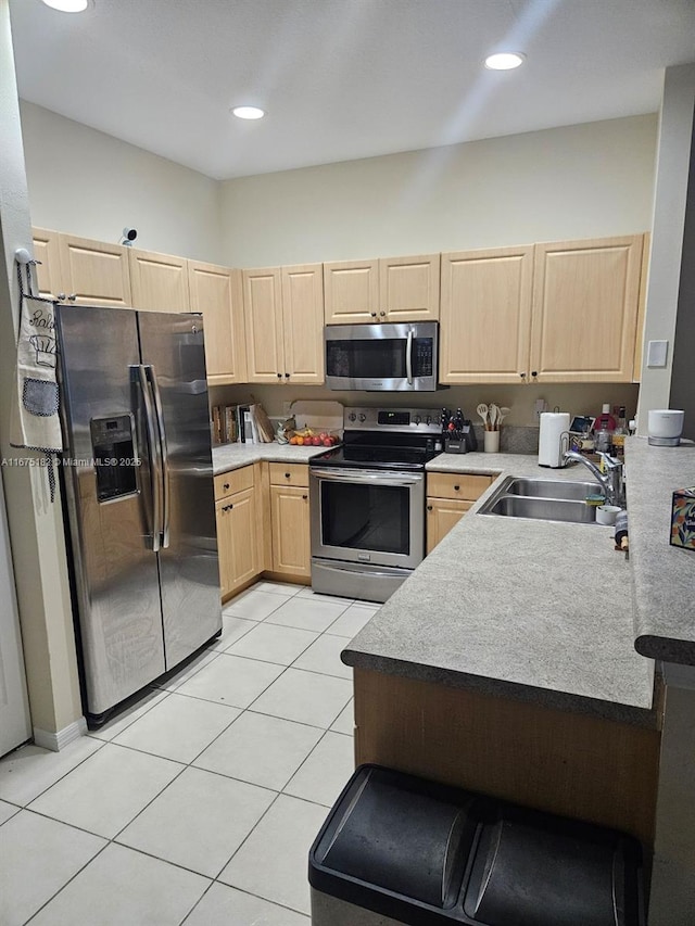 kitchen featuring sink, light brown cabinetry, light tile patterned flooring, and appliances with stainless steel finishes