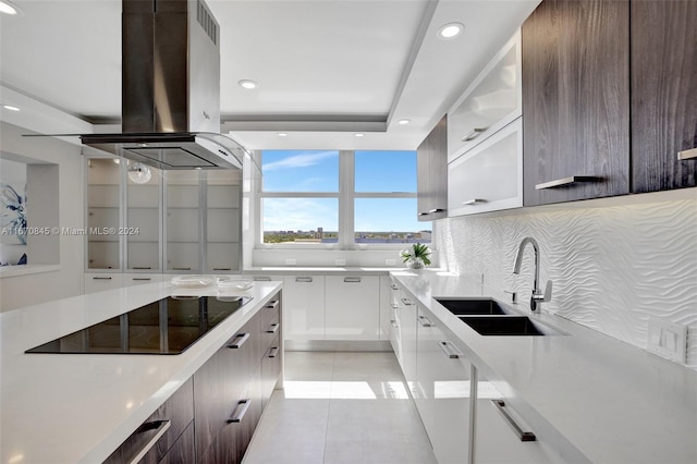 kitchen featuring tasteful backsplash, sink, white cabinets, island range hood, and black electric stovetop