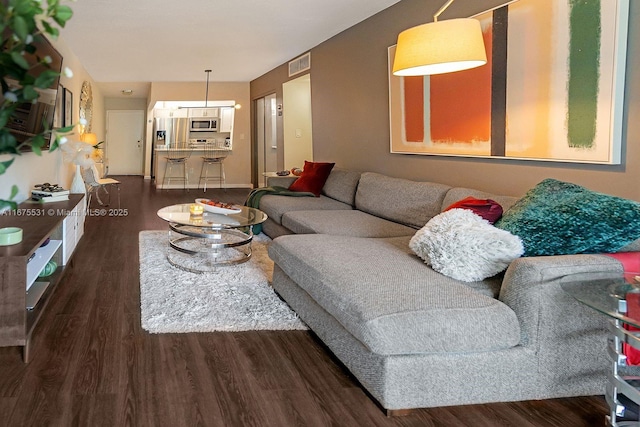 living area with dark wood-style flooring and visible vents