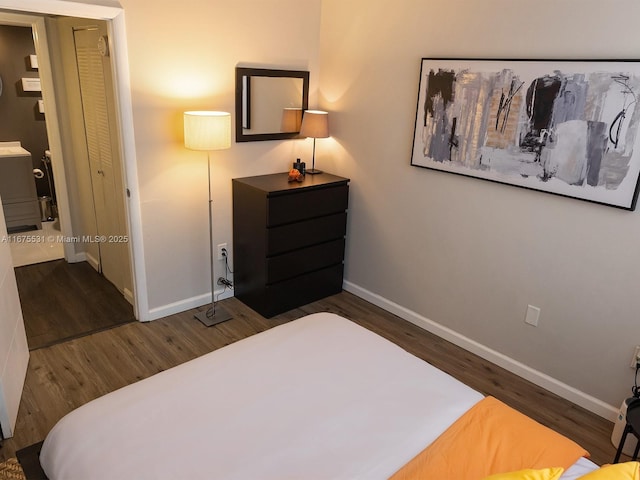 bedroom with dark wood-style floors, baseboards, and washer / dryer