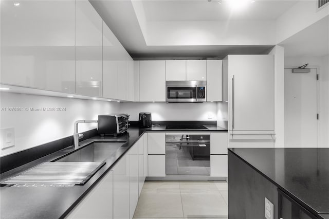 kitchen featuring appliances with stainless steel finishes, white cabinetry, sink, and light tile patterned flooring