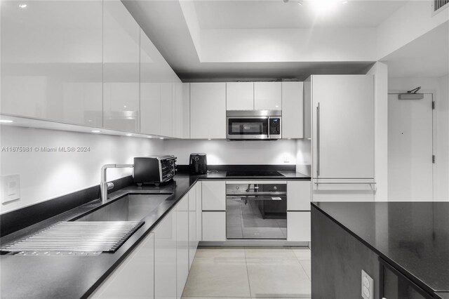 1010 Brickell Ave Unit 1607, Miami, FL 33131 - kitchen with dark countertops, a sink, white cabinetry, modern cabinets, and black appliances