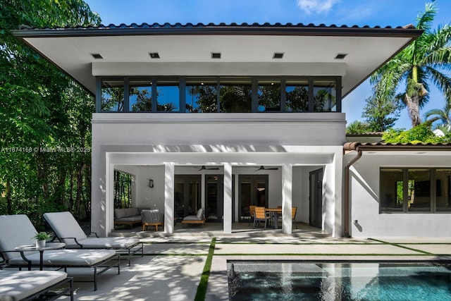 rear view of property with ceiling fan, an outdoor living space, and a patio area