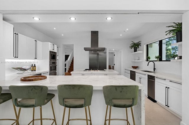 kitchen featuring a breakfast bar, ventilation hood, white cabinetry, sink, and light stone counters