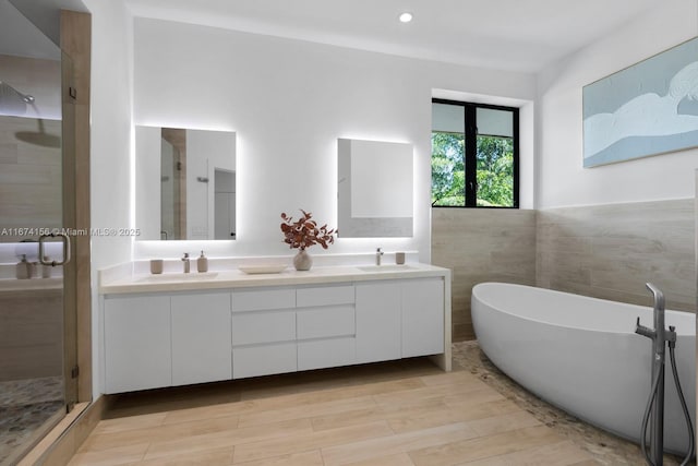 bathroom with hardwood / wood-style flooring, vanity, separate shower and tub, and tile walls