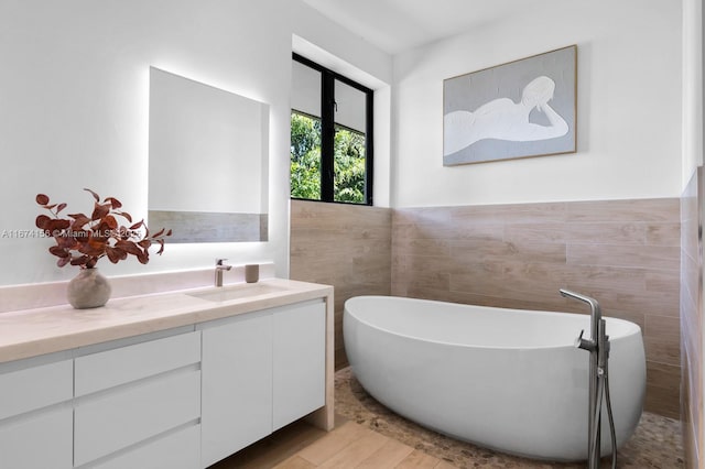 bathroom with vanity, a bath, hardwood / wood-style flooring, and tile walls