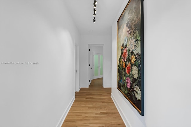 hall with light hardwood / wood-style flooring and track lighting