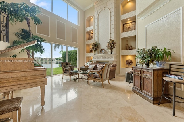 living area featuring a towering ceiling, crown molding, and a water view