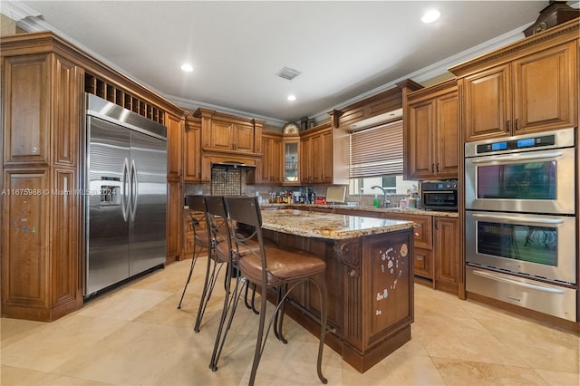 kitchen with stainless steel appliances, ornamental molding, a center island, and a kitchen bar