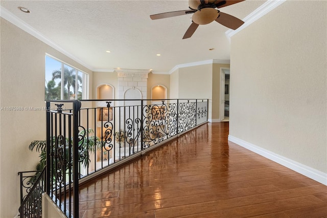 corridor with ornamental molding, hardwood / wood-style floors, and a textured ceiling