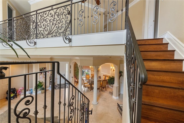 staircase featuring crown molding, a notable chandelier, and decorative columns