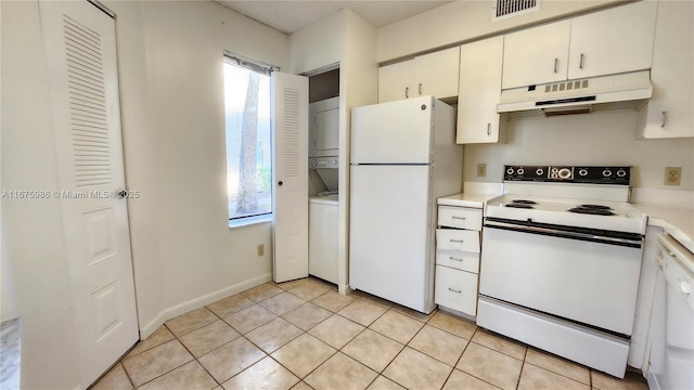 kitchen featuring stacked washing maching and dryer, light tile patterned floors, white appliances, and white cabinetry