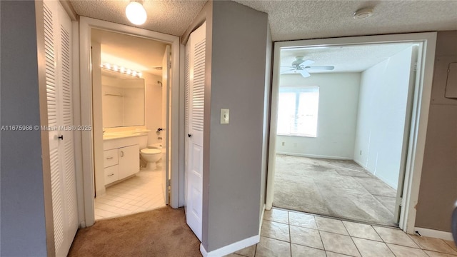 hall with light carpet and a textured ceiling