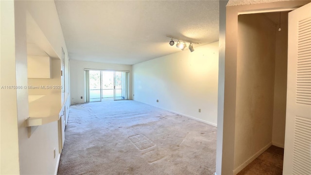 carpeted empty room with a textured ceiling and rail lighting