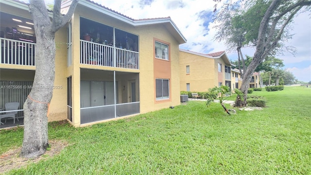 rear view of property with central AC unit and a lawn