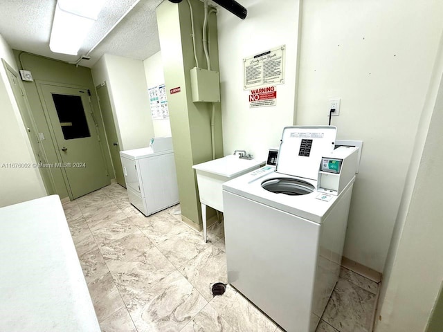 washroom with a textured ceiling, sink, and separate washer and dryer