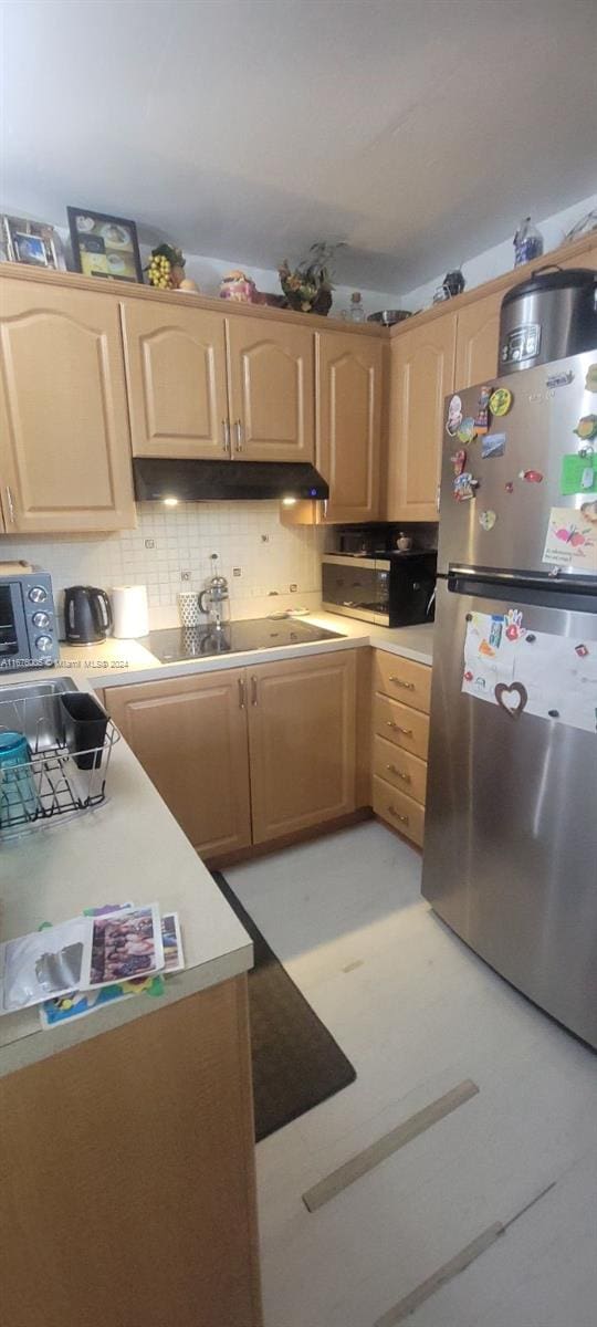 kitchen with light brown cabinets, tasteful backsplash, and stainless steel refrigerator