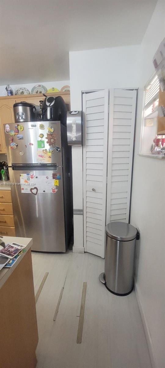 kitchen with light wood-type flooring, light brown cabinets, and stainless steel fridge