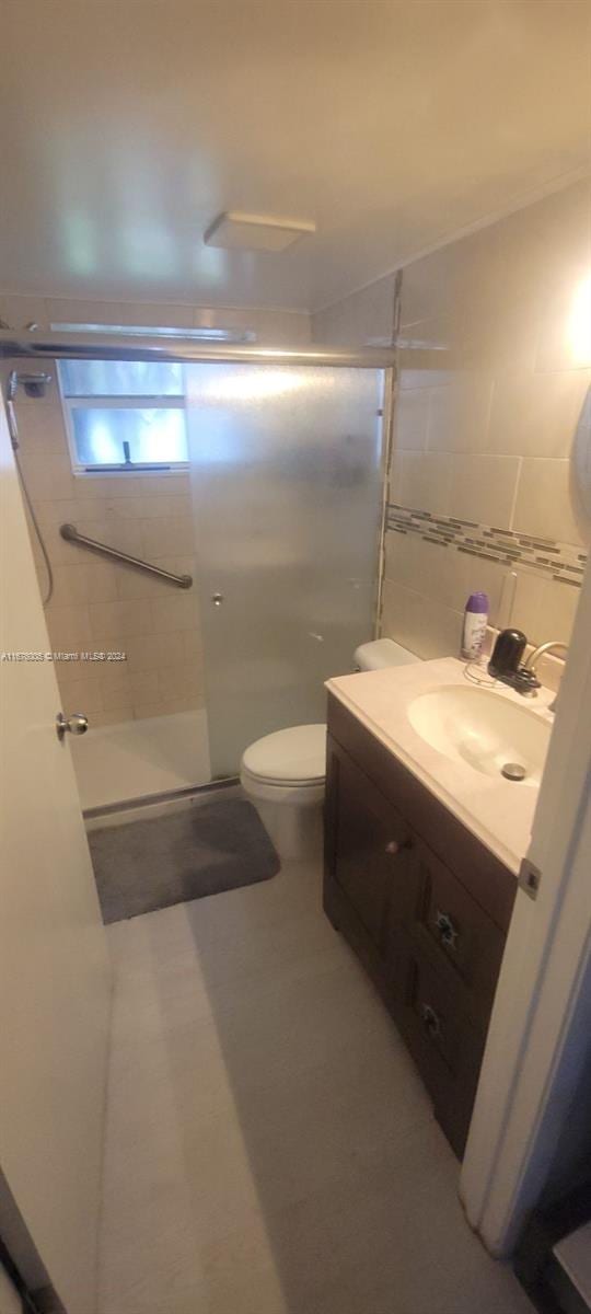 bathroom with vanity, toilet, and a shower with door