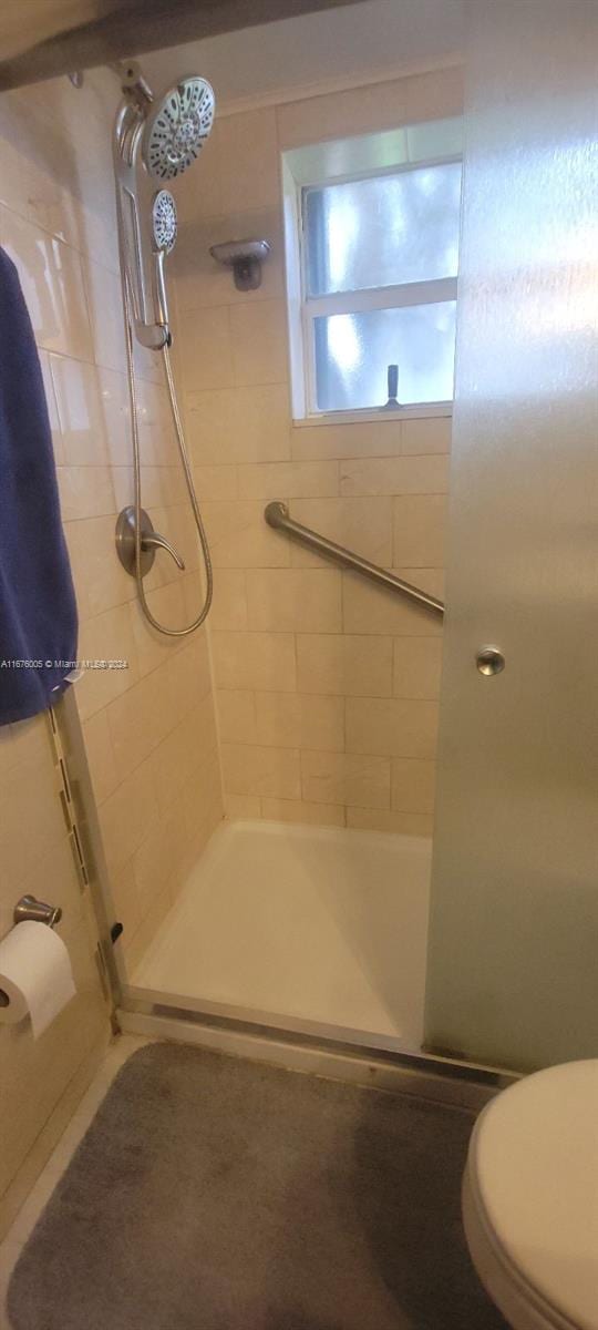 bathroom with a shower with door and toilet