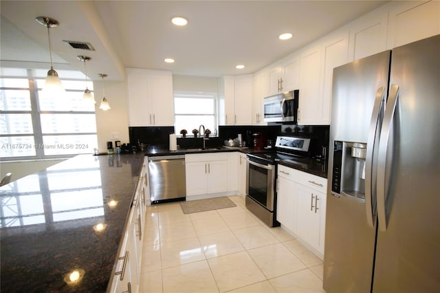 kitchen with white cabinets, tasteful backsplash, decorative light fixtures, appliances with stainless steel finishes, and dark stone counters