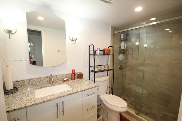 bathroom with walk in shower, vanity, and toilet