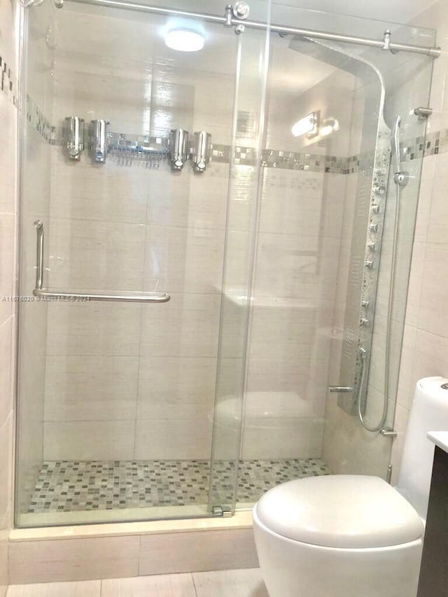 bathroom with tile patterned flooring, vanity, a shower with door, and toilet