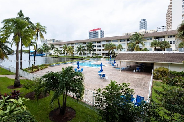 view of swimming pool featuring a patio, a lawn, and a water view