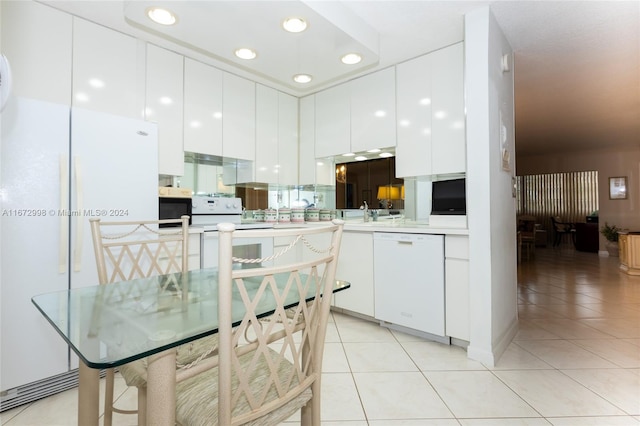 kitchen featuring white cabinets, kitchen peninsula, white appliances, and light tile patterned floors