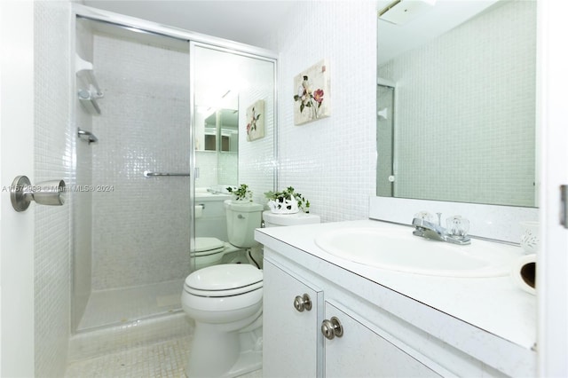 bathroom featuring toilet, a shower with shower door, vanity, and tile patterned flooring