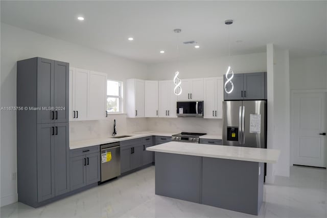 kitchen with gray cabinets, a kitchen island, pendant lighting, appliances with stainless steel finishes, and white cabinetry