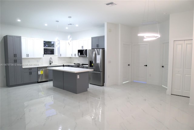 kitchen featuring stainless steel appliances, hanging light fixtures, gray cabinetry, and a kitchen island