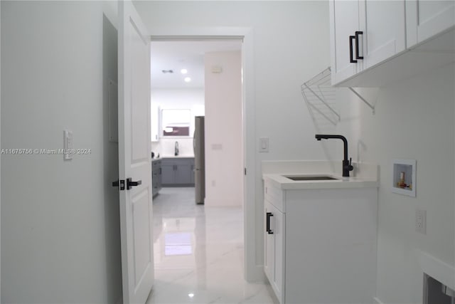 clothes washing area with hookup for a washing machine, cabinets, and sink