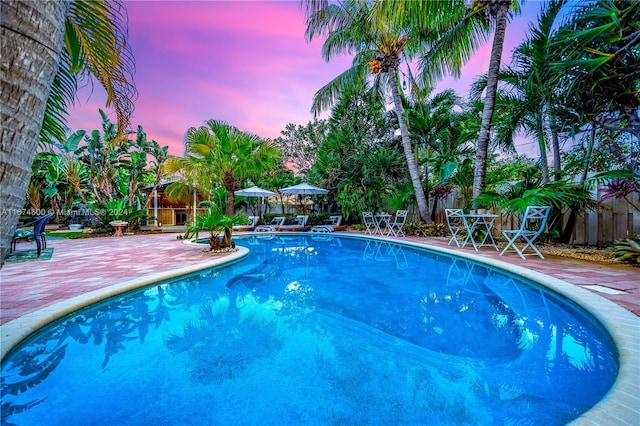 pool at dusk with a patio area