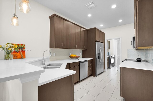 kitchen with stainless steel appliances, decorative light fixtures, sink, and dark brown cabinetry