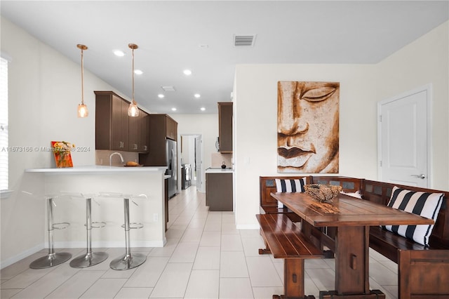 kitchen with stainless steel refrigerator with ice dispenser, hanging light fixtures, dark brown cabinets, and kitchen peninsula