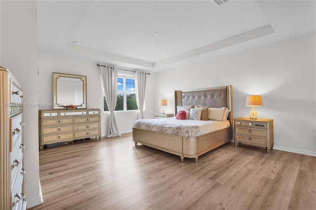 bedroom featuring a tray ceiling and light hardwood / wood-style flooring