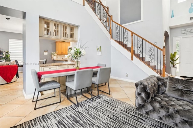 dining area featuring a towering ceiling, plenty of natural light, and light tile patterned floors