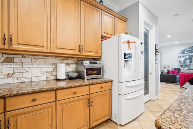 kitchen featuring white refrigerator, decorative backsplash, ornamental molding, light tile patterned flooring, and stone countertops