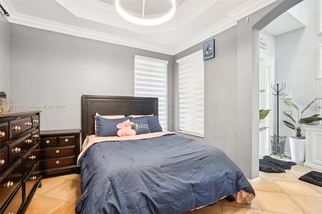 bedroom with a raised ceiling, light tile patterned floors, and crown molding