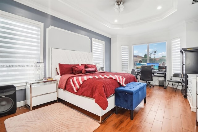 bedroom with ceiling fan, wood-type flooring, crown molding, and a raised ceiling