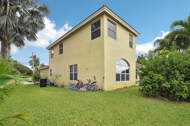 back of house with central AC and a yard