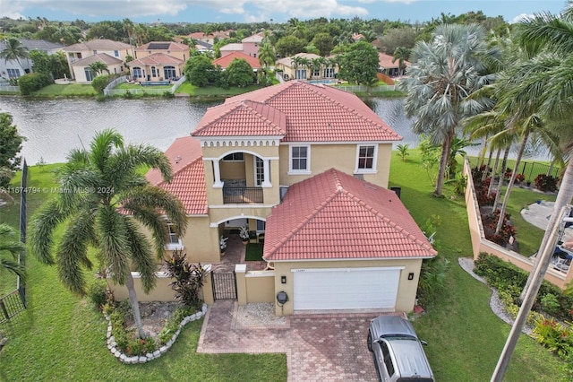 view of front of house with a garage, a water view, a front lawn, and a balcony