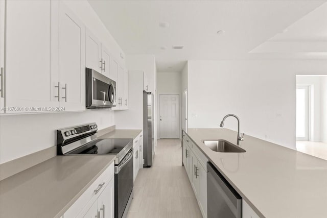 kitchen featuring light hardwood / wood-style floors, appliances with stainless steel finishes, sink, and white cabinetry