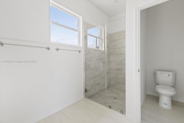 bathroom featuring toilet and a shower with shower door