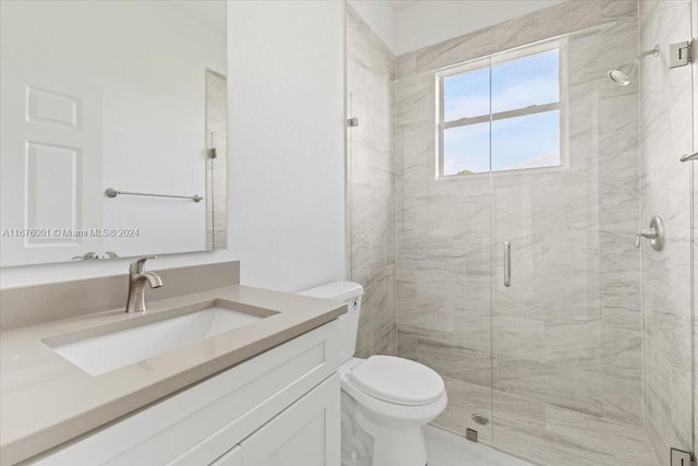 bathroom featuring vanity, a shower with door, and toilet